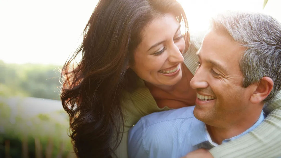 A woman hugging her husband while enjoying a walk outdoors.