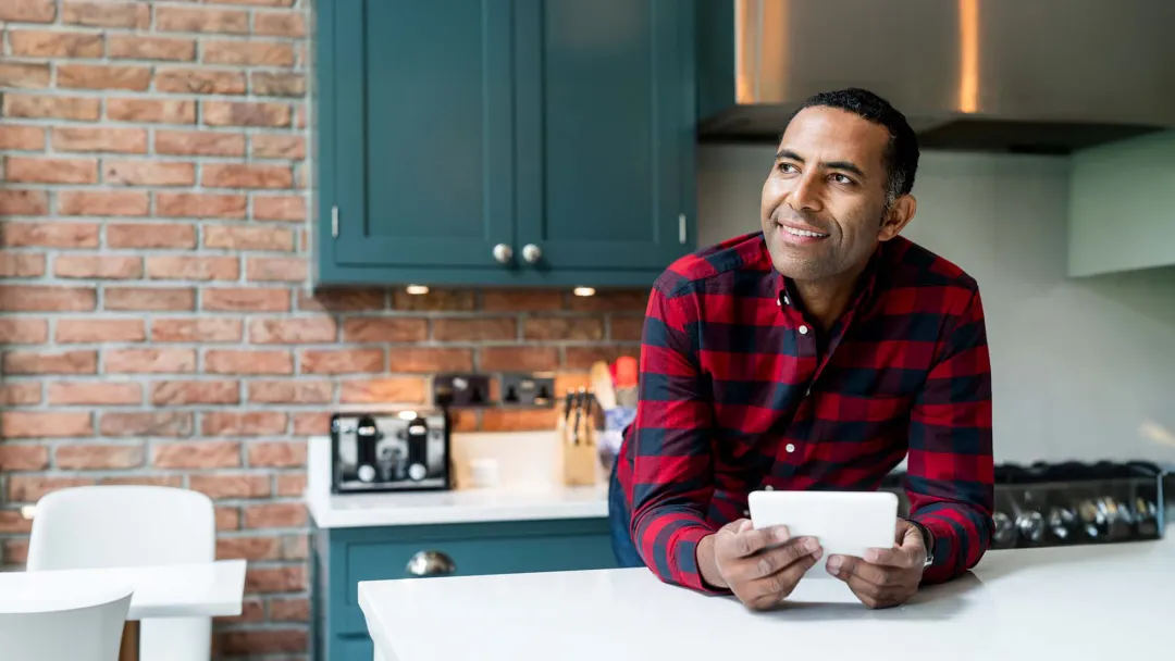 Smiling Man in Home Kitchen with a Tablet