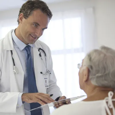 A Caucasian male doctor consults with a female patient at the hospital.