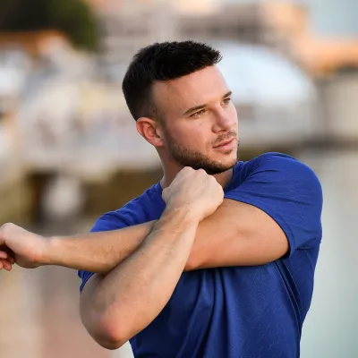 A young man stretching outdoors.