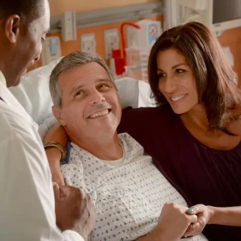 Male patient in hospital bed talking with doctor