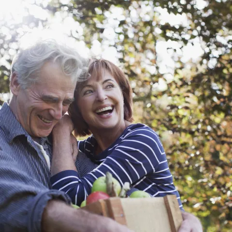 Senior couple smiling and embracing after picking up some apples
