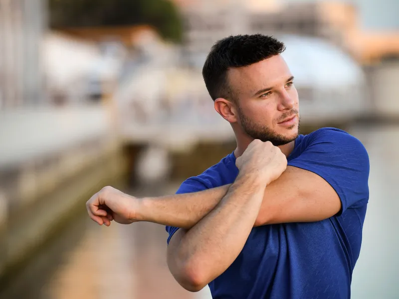 A young man stretching outdoors.
