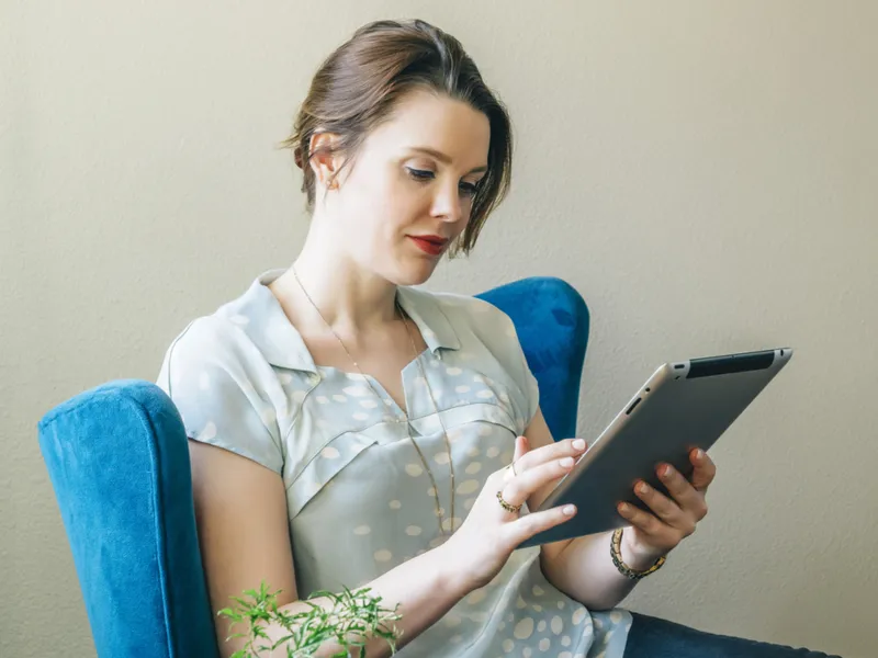 A young caucasian woman reads from her tablet indoors.