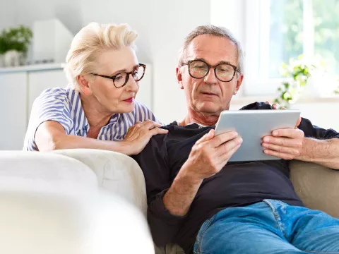 A senior couple focused on the tablet they carry